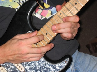 closeup photo of Andy tapping on his Strat